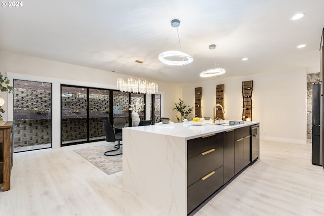 kitchen featuring dishwasher, sink, hanging light fixtures, light wood-type flooring, and a large island