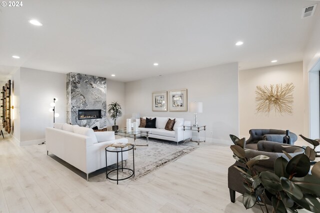 living room with light wood-type flooring and a high end fireplace