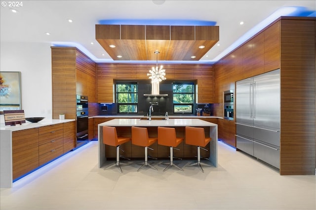 kitchen with hanging light fixtures, a center island with sink, a notable chandelier, and sink