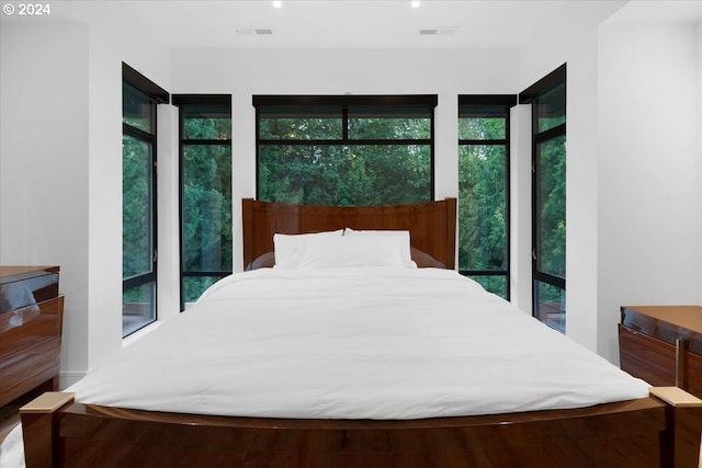 bedroom with hardwood / wood-style flooring and multiple windows