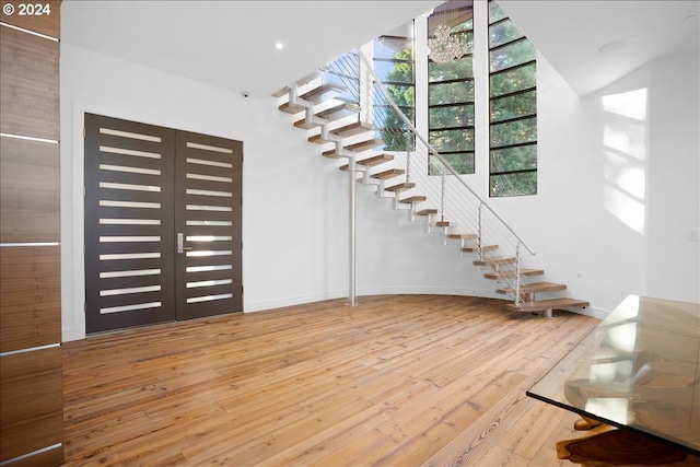 stairway with light hardwood / wood-style floors and french doors