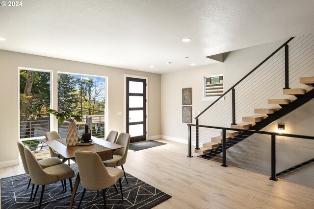 dining area with a textured ceiling and light hardwood / wood-style floors