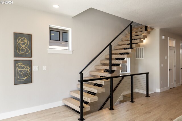 stairway with light hardwood / wood-style flooring