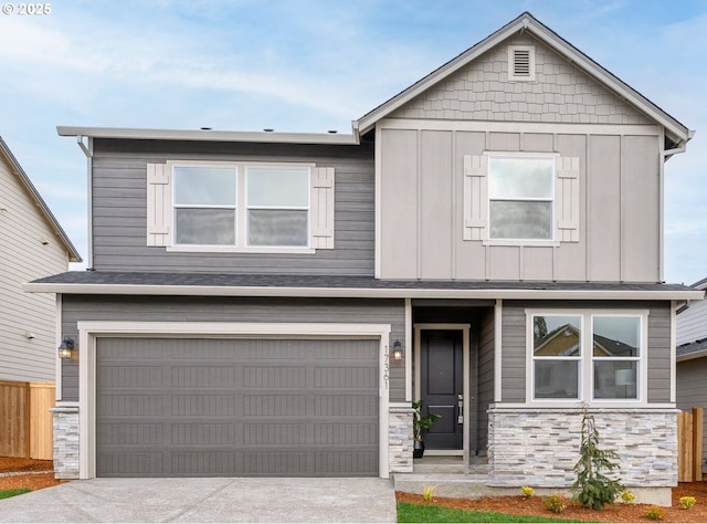 view of front of property featuring fence, driveway, stone siding, a garage, and board and batten siding