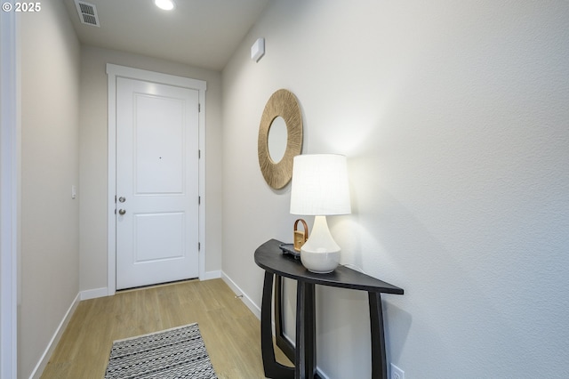 doorway featuring visible vents, light wood-type flooring, and baseboards