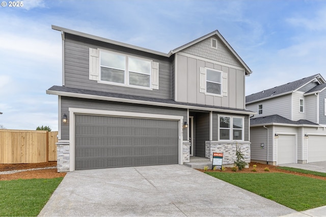 craftsman inspired home with board and batten siding, fence, concrete driveway, a garage, and stone siding