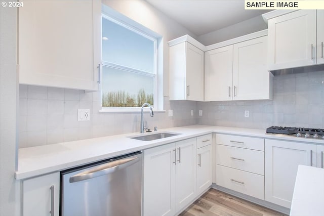 kitchen featuring sink, white cabinets, backsplash, stainless steel appliances, and light hardwood / wood-style flooring