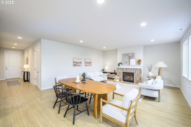 dining space featuring recessed lighting, light wood-style flooring, and a tile fireplace