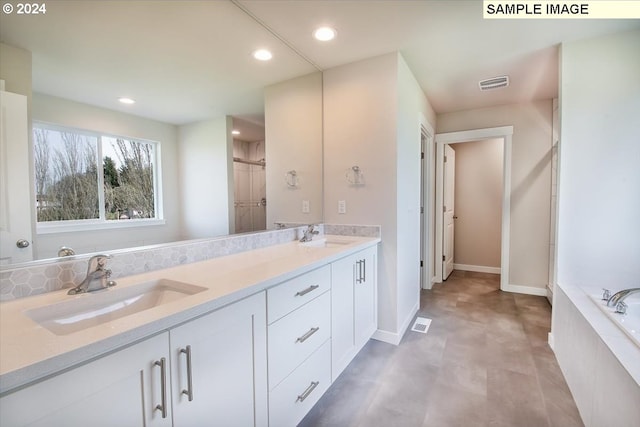 bathroom featuring vanity and tiled bath