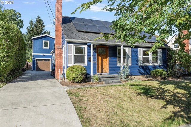 view of front of property featuring a garage, solar panels, and a front lawn