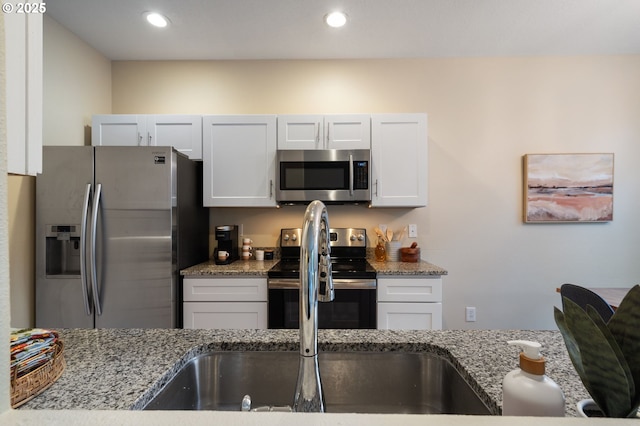 kitchen with white cabinets, light stone countertops, and stainless steel appliances