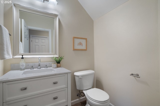 bathroom with vanity, toilet, and lofted ceiling