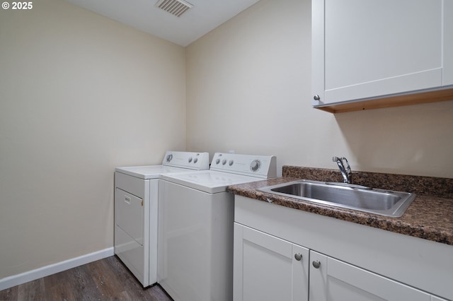 laundry area featuring washing machine and clothes dryer, sink, cabinets, and dark hardwood / wood-style floors