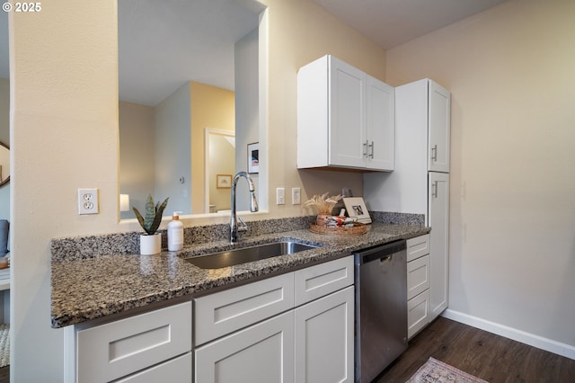 kitchen with stainless steel dishwasher, dark stone counters, dark wood-type flooring, sink, and white cabinetry