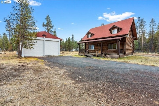 view of front facade with an outbuilding, a garage, and a porch