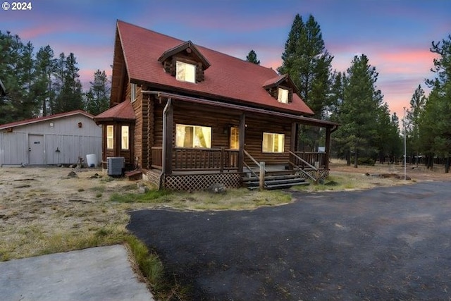 log-style house with central AC unit and a porch