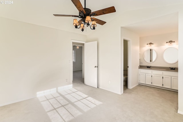 unfurnished bedroom with baseboards, vaulted ceiling, a sink, and light colored carpet