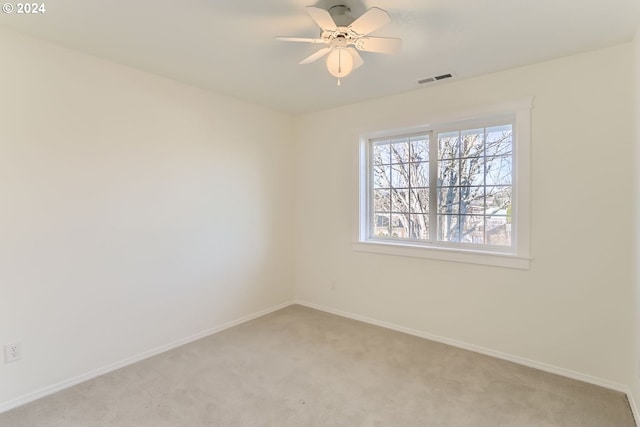 empty room with visible vents, baseboards, a ceiling fan, and light colored carpet