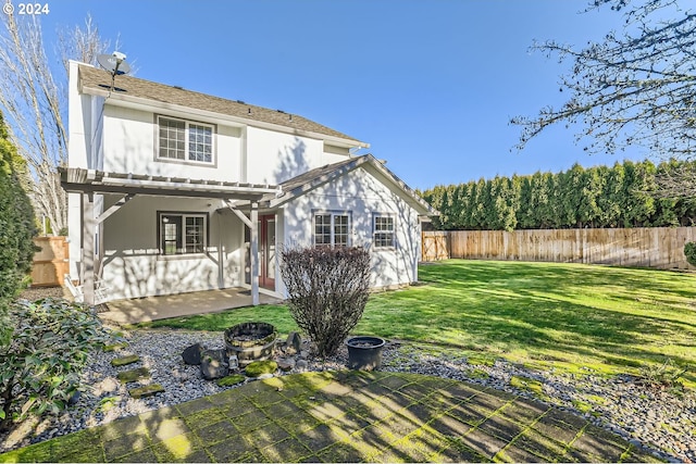 back of house featuring an outdoor fire pit, fence, a lawn, and a patio