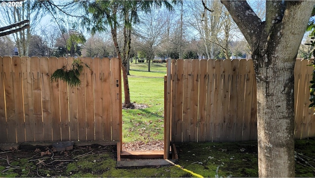 view of gate with a yard and fence