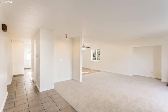 spare room featuring a ceiling fan, light tile patterned flooring, light carpet, and baseboards