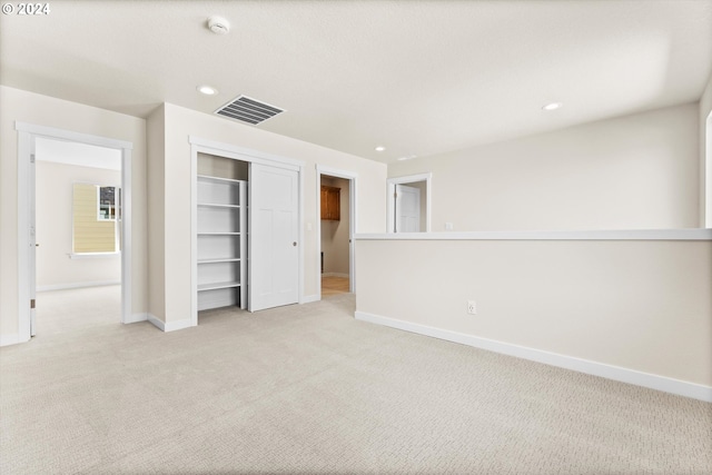 unfurnished bedroom with light colored carpet and a closet