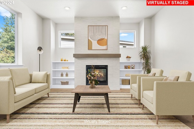 living room with light hardwood / wood-style flooring, a fireplace, and a healthy amount of sunlight