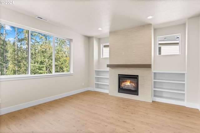 unfurnished living room with a textured ceiling, a fireplace, hardwood / wood-style floors, and a wealth of natural light