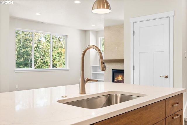 kitchen featuring hanging light fixtures, a fireplace, and sink