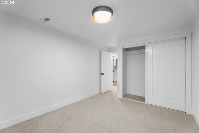 unfurnished bedroom featuring a closet and light carpet