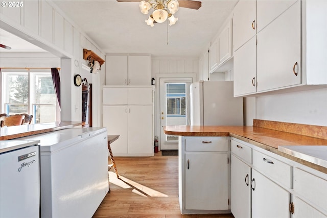 kitchen featuring freestanding refrigerator, light countertops, ceiling fan, and white cabinetry