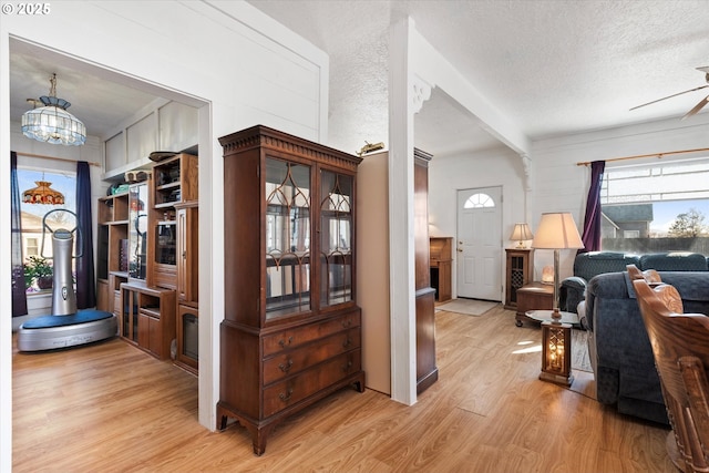 interior space featuring light wood-style floors, a textured ceiling, and ceiling fan with notable chandelier