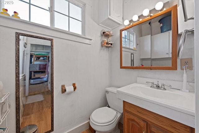 bathroom with toilet, baseboards, wood finished floors, and vanity