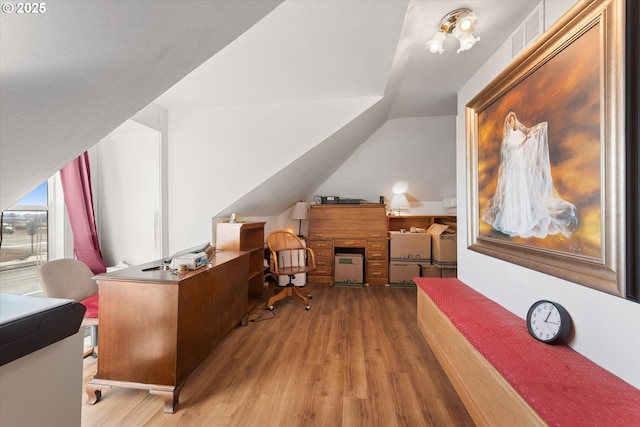 home office featuring lofted ceiling, light wood-style floors, and visible vents