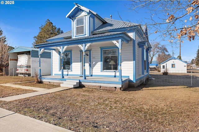 view of front of house with covered porch, metal roof, and a front yard