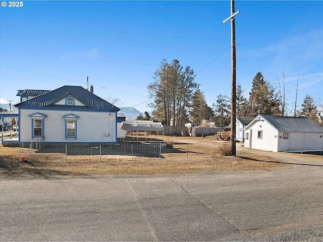 view of side of home featuring fence and an outdoor structure