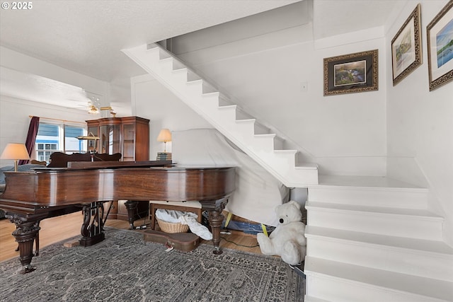 stairway featuring a textured ceiling, wood finished floors, and a ceiling fan