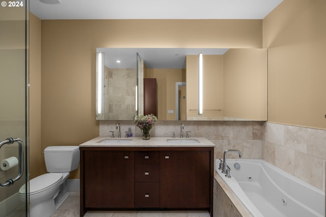 bathroom featuring vanity, a relaxing tiled tub, and toilet