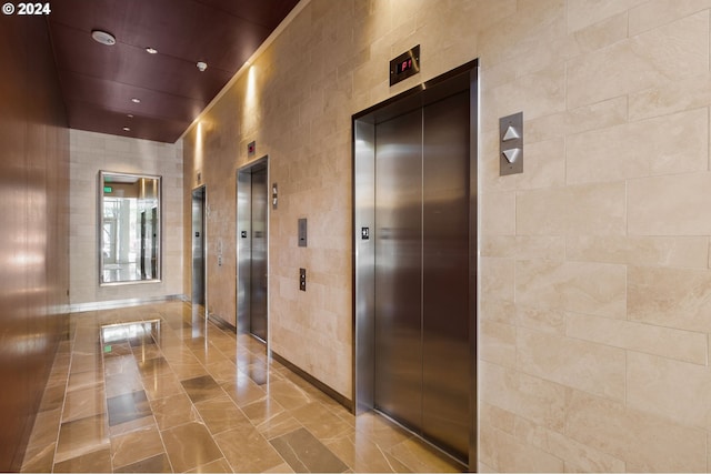 corridor featuring tile walls and elevator