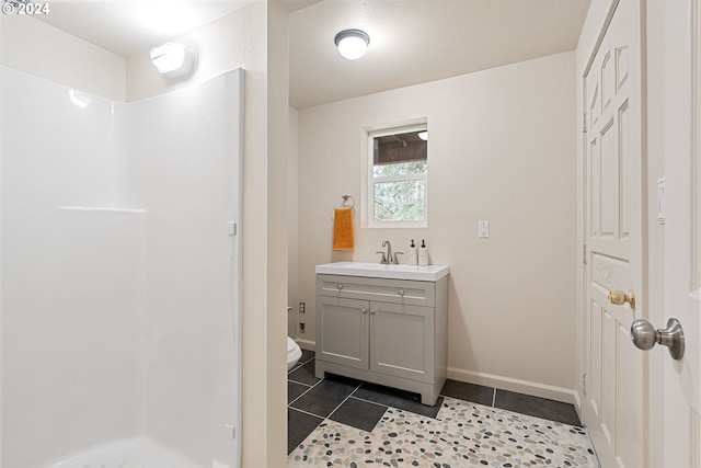 bathroom with tile patterned floors, vanity, toilet, and a shower