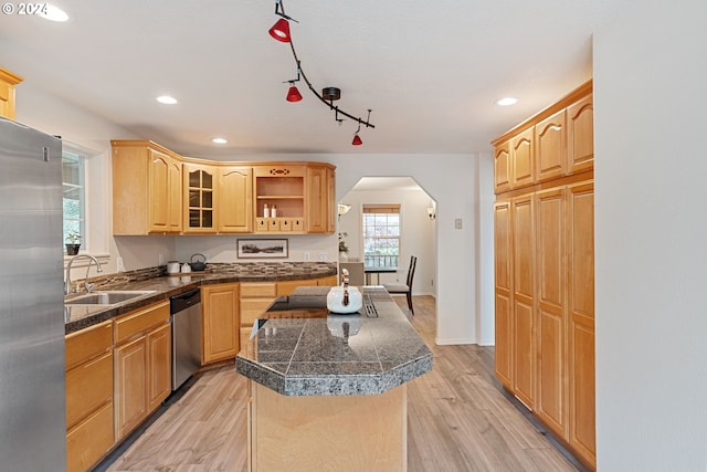 kitchen with rail lighting, stainless steel appliances, sink, light hardwood / wood-style flooring, and a center island