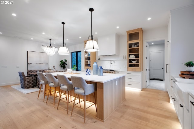 kitchen with hanging light fixtures, a kitchen island, light hardwood / wood-style floors, and a breakfast bar