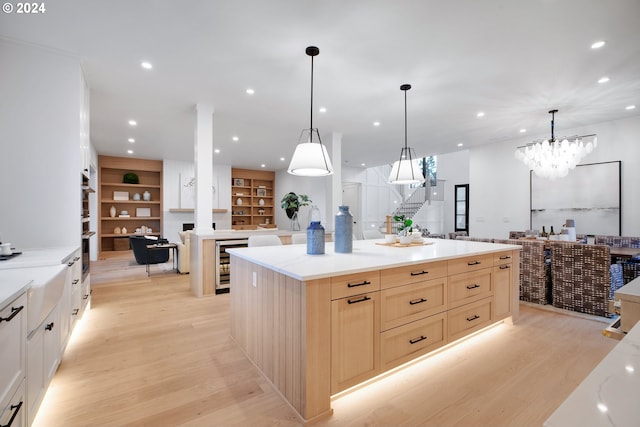 kitchen with wine cooler, decorative light fixtures, a fireplace, light hardwood / wood-style flooring, and a center island