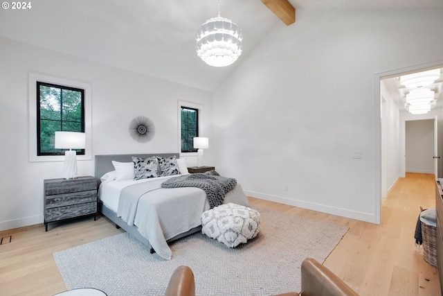 bedroom with lofted ceiling with beams, light hardwood / wood-style flooring, and a notable chandelier