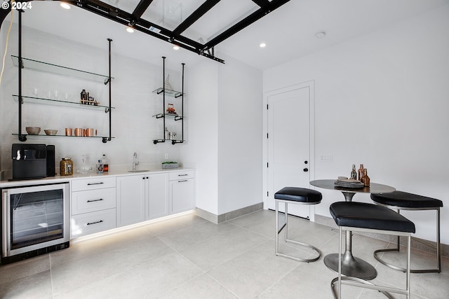 bar with beverage cooler, sink, and white cabinets