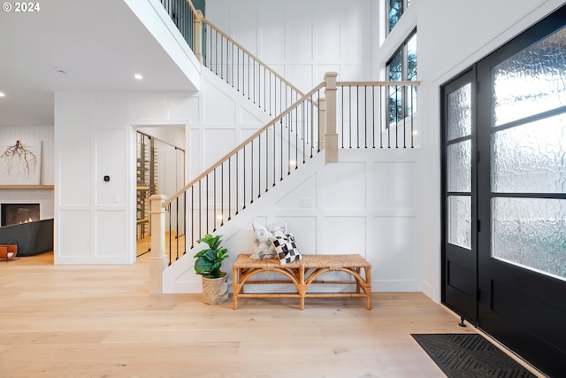 foyer entrance with a premium fireplace, a high ceiling, and light hardwood / wood-style floors