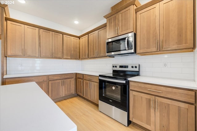 kitchen featuring stainless steel appliances, decorative backsplash, and light hardwood / wood-style flooring