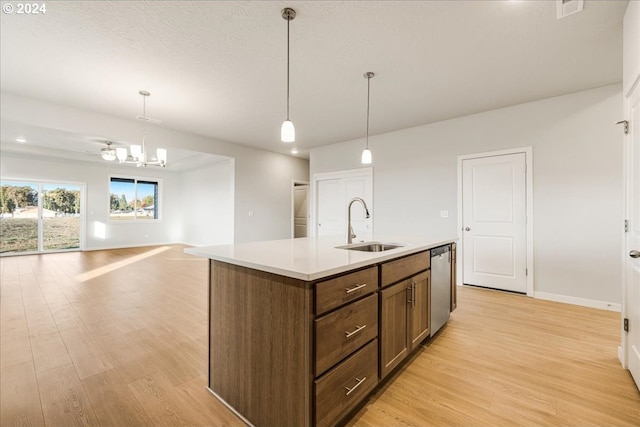 kitchen featuring a center island with sink, dishwasher, decorative light fixtures, and light wood-type flooring