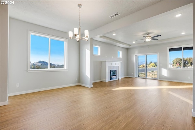 unfurnished living room featuring a tiled fireplace, ceiling fan with notable chandelier, and light wood-type flooring