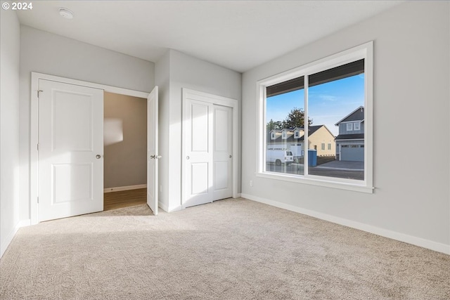 unfurnished bedroom with light colored carpet and a closet